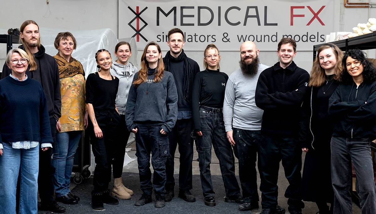 Das Team von MEDICAL FX vor einem Banner mit dem Logo